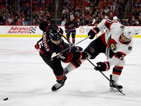 Jalen Chatfield of the Hurricanes and Mathieu Joseph of the Senators battle for possession during the third period.