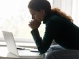 Worried woman sits in front of laptop.