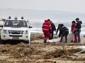 Rescuers recover a body after a suspected migrant boat is wrecked and bodies believed to be of refugees were found in Cutro, the eastern coast of Italy's Calabria region, on Sunday, Feb. 26, 2023.