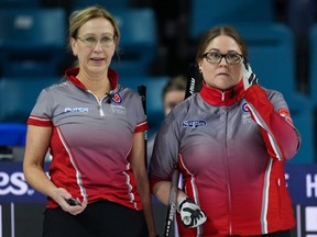 Northwest Territories fourth Jo-Ann Rizzo, left, uses a stopwatch to time a rock as skip Kerry Galusha adjusts her glasses while Ontario plays a shot at the Scotties Tournament of Hearts, in Kamloops, B.C., Sunday, Feb. 19, 2023.
