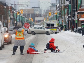 A dad pulls his two kids across Bank Street with the help of a crossing guard in Ottawa Friday.  More snow is on the way.
