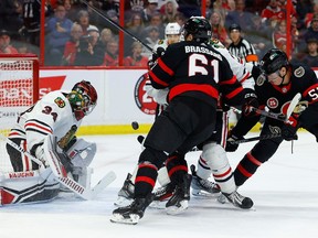 Senators forwards Derick Brassard (61) and Shane Pinto (57) battle for a rebound after the save was made by Blackhawks goaltender Petr Mrazek (34) during the first period of Friday's game at Canadian Tire Centre.