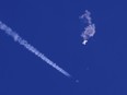 In this photo provided by Chad Fish, the remnants of a large balloon drift above the Atlantic Ocean, just off the coast of South Carolina, with a fighter jet and its contrail seen below it, Feb. 4, 2023.