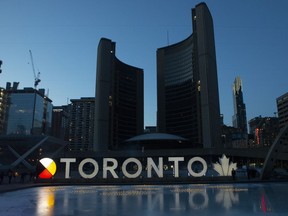 As Toronto looks to elect a new mayor in the coming months, observers say international investors are looking for a business-savvy leader like John Tory to take the helm. Tory is silhouetted against an illuminated sign during a Commemorative Ceremony in Toronto, Sunday, March 20, 2021.