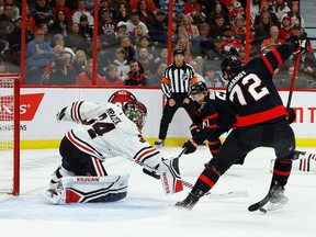 The puck slides between the skates of Senators defenceman Thomas Chabot as he looks at an open Blackhawks net in the first period of Friday's game.