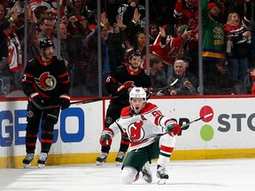 Jack Hughes of the Devils celebrates in front of Senators defencemen Travis Hamonic, left, and Erik Brannstrom after scoring a spectacular first-period goal on Saturday night.