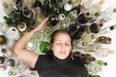 Young woman in jeans and t-shirt sitting on the floor with lots of empty beer bottles and is drunk.