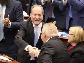 Ontario Finance Minister Peter Bethlenfalvy (left) shakes hands with Premier Doug Ford after tabling the provincial budget as Health Minister Sylvia Jones looks on at the legislature at Queen's Park in Toronto on Thursday, March 23, 2023.