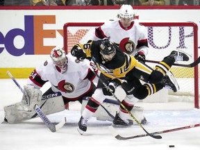 The Pittsburgh Penguins' Jason Zucker is checked to the ice by the Ottawa Senators' Jakob Chychrun in front of goaltender Dylan Ferguson during the first period in Pittsburgh on Monday, March 20, 2023.