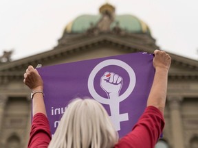A woman brandishes a flag with the symbol of a nationwide women's strike in front of the Federal Palace of Switzerland on June 14, 2019.