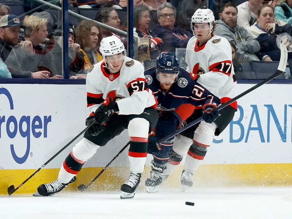 Josh Dunne of the Columbus Blue Jackets attempts to beat Shane Pinto (No. 57) of the Ottawa Senators and Ridly Greig to a loose puck during the second period.