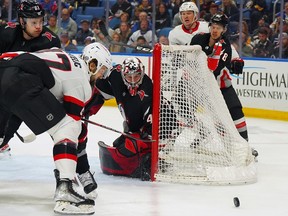 Sabres netminder and former Senator Craig Anderson and Ottawa's Mark Kastelic watch the rolling puck near the crease during the first period of Thursday's game in Buffalo.