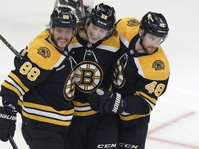 Boston Bruins' David Pastrnak (left) celebrates his goal with Tyler Bertuzzi and defenceman Matt Grzelcyk during the second period against the Montreal Canadiens, Thursday, March 23, 2023, in Boston.