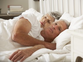 Older woman in bed with husband who appears worried.