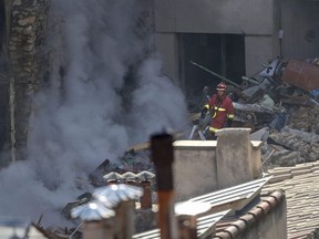 A firefighter walks amongst the rubble after a building collapsed in the street, in Marseille, France, Sunday, April 9, 2023.