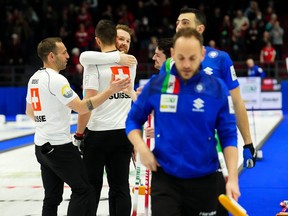 Swiss second Sven Michel, left to right, Swiss lead Pablo Lachat, Swiss skip Yannick Schwaller and Swiss vice-skip Benoit Schwarz celebrate their win as Italian skip Joel Retornaz and Italian second Sebastiano Arman make their way to shake hands with the Swiss coaches following the bronze medal game at the men’s world curling championship in Ottawa on Sunday, April 9, 2023.