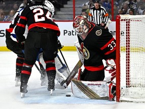 Senators goaltender Cam Talbot (33) keeps his eye on the puck after a save as the skate of Lightning centre Michael Eyssimont (23) clips his stick during the first period of Saturday's contest.