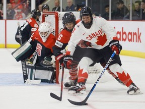 Canada's Laura Stacey (7) protects the puck from Japanese defender Shiori Yamashita during the first period of Saturday's game at Brampton, Ont.