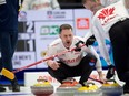 Canadian skip Brad Gushue shouts to second E.J.Harnden, right, and lead Geoff Walker as they brush a stone from third Mark Nichols into the house in the fourth end of Friday evening's game against Sweden.