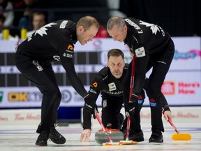 Canadian skip Brad Gushue delivers a stone as lead Geoff Walker, left, and second E.J. Harnden provide the sweeping during Saturday night's semifinal against Switzerland.