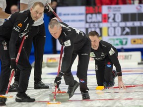 Canadian skip Brad Gushue, right, follows the path of his stone as lead Geoff Walker, left, and second E.J. Harnden sweep ti in the evening draw against Italy.