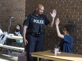 This file photo shows Toronto Police officer Alphonso Carter, a school resource officer, walking the halls of Cardinal Newman High School greeting and talking with students on June 12, 2017.