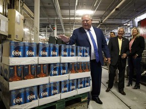 Ontario Premier Doug Ford slaps the top of boxes of beer as Ontario Finance Minister Vic Fedeli laughs in background at a brewery in Etobicoke, Ont., Monday, Aug. 27, 2018.