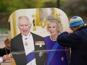 A man erects a life size cut-out of King Charles III and Camilla, Queen Consort on the Mall as preparations continue for The Coronation on May 05, 2023 in London, England. The Coronation of King Charles III and The Queen Consort will take place on May 6, part of a three-day celebration.
