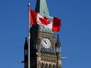 A Canadian flag flies in front of the Peace Tower on Parliament Hill.