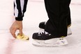 A referee picks up a hot dog off of the ice that was thrown from the stands during the first shootout attempt by Tyler Seguin of the Boston Bruins against the New Jersey Devils during the game on January 29, 2013 at TD Garden in Boston, Massachusetts. (Photo by Jared Wickerham/Getty Images)