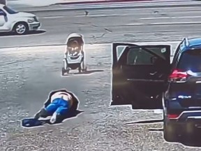 A woman identified as the great-aunt of the infant lies on the ground after falling as a stroller rolls backward towards traffic in Hesperia, Calif., on Monday, May 1, 2023.
