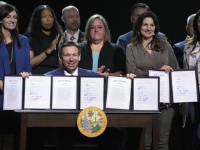 Florida Gov. Ron DeSantis holds up bills he signed during a bill signing ceremony at the Coastal Community Church at Lighthouse Point, Tuesday, May 16, 2023, in Lighthouse Point, Fla.