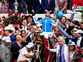Jockey Javier Castellano celebrates aboard Mage in the Winner's Circle as trainer Gustavo Delgado , with a hand on the garland of roses, won the 149th Kentucky Derby on Saturday.