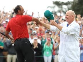 Tiger Woods (L) of the United States celebrates with caddie Joe LaCava (R) on the 18th green after winning during the final round of the Masters at Augusta National Golf Club on April 14, 2019.