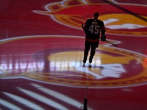 Senators' Parker Kelly skates as projections of the team's logo spin on the ice.