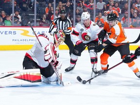 Ottawa Senators and Philadelphia Flyers hockey players scuffle in front of Ottawa's net.