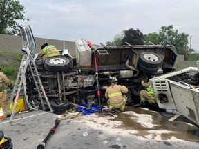Ottawa Fire Service crew members work on a truck that rolled on the westbound section of Highway 174 on Friday, injuring two occupants.