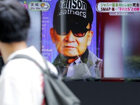 A passer-by watches news reporting on the death of Johnny Kitagawa, founder of Johnny's talent agency, in Tokyo, July 10, 2019.