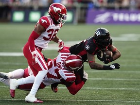 Ottawa Redblacks wide receiver Justin Hardy is tackled by two Calgary Stampeders.
