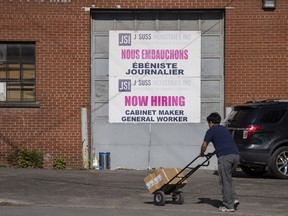 Worker walks past a Now Hiring sign