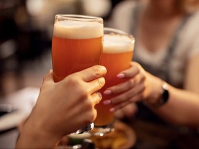 Closeup of two people toasting with lager beer in a bar.