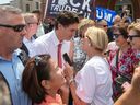 Prime Minister Justin Trudeau speaks with people as protesters shout at him in Belleville on Thursday July 20, 2023.