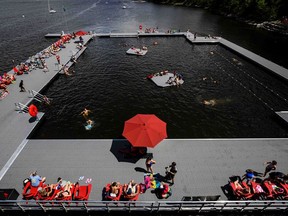 People sunbathe and swim in the Ottawa River at the NCC River House