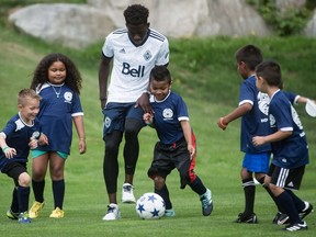 Alphonso Davies, centre left, plays soccer with kids
