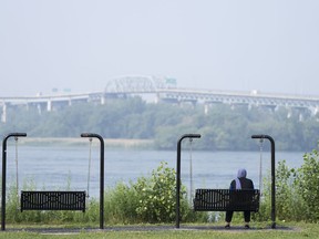 Smoke from fires in western and northern parts of Canada has created a hazardous air quality in Ontario's north. A woman looks out at the St. Lawrence River in LaSalle, Que., Friday, June 30, 2023.