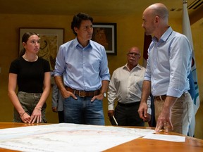 Prime Minister Justin Trudeau looks over a map outlining the McDougall Creek wildfire with Loyal Wooldridge, chair of the Regional District Central Okanagan, as his daughter Ella-Grace looks on in West Kelowna, B.C., on Friday, Aug. 25, 2023.
