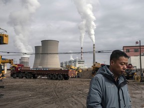 A person walks past a coal-fired power plant in Jiayuguan, Gansu province, China