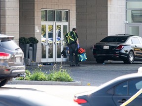 With police evidence markers on the ground behind him an Ottawa paramedic leaves the scene of a mass shooting outside a wedding reception