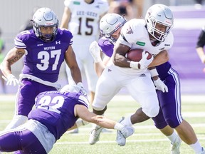 Amlicar Polk of the Ottawa Gee Gees is tackled by Western Mustangs' Jordan Murphy (22) and Emerson Paleczny during a game last month.