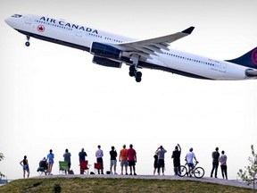 Plane spotters watch an Air Canada Airbus A330-300 jet take off from Trudeau Airport in Dorval, Que., June 23, 2023.
